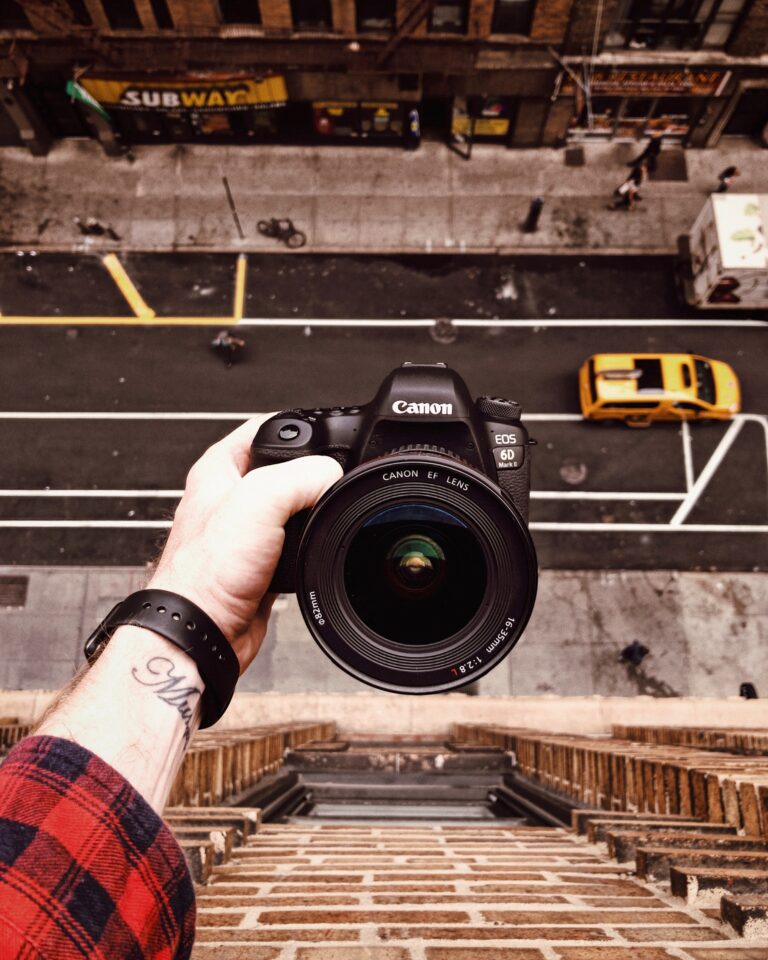 Man leaning over the edge of a window to film himself