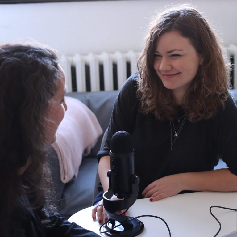 Two women speaking over a microphone