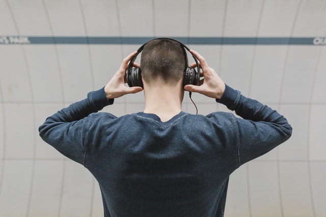 man holding earphones to his ears - clubhouse social media app
