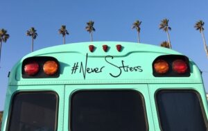 turquoise bus in front of palm trees with the phrase # never stress on back