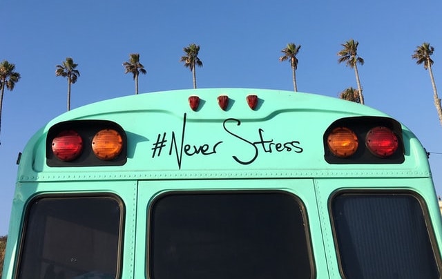 turquoise bus in front of palm trees with the phrase # never stress on back