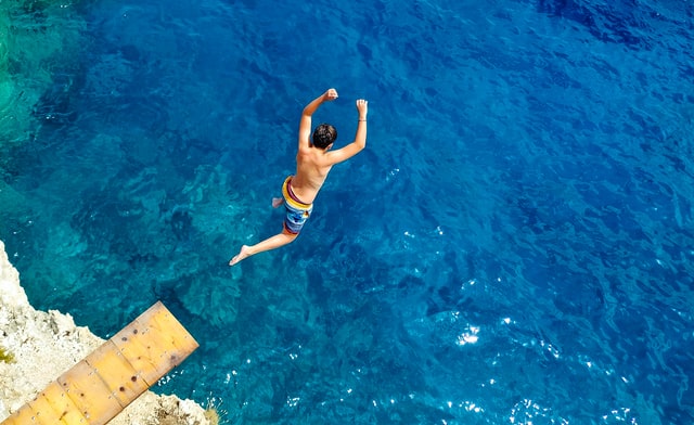 man plunging into blue ocean water