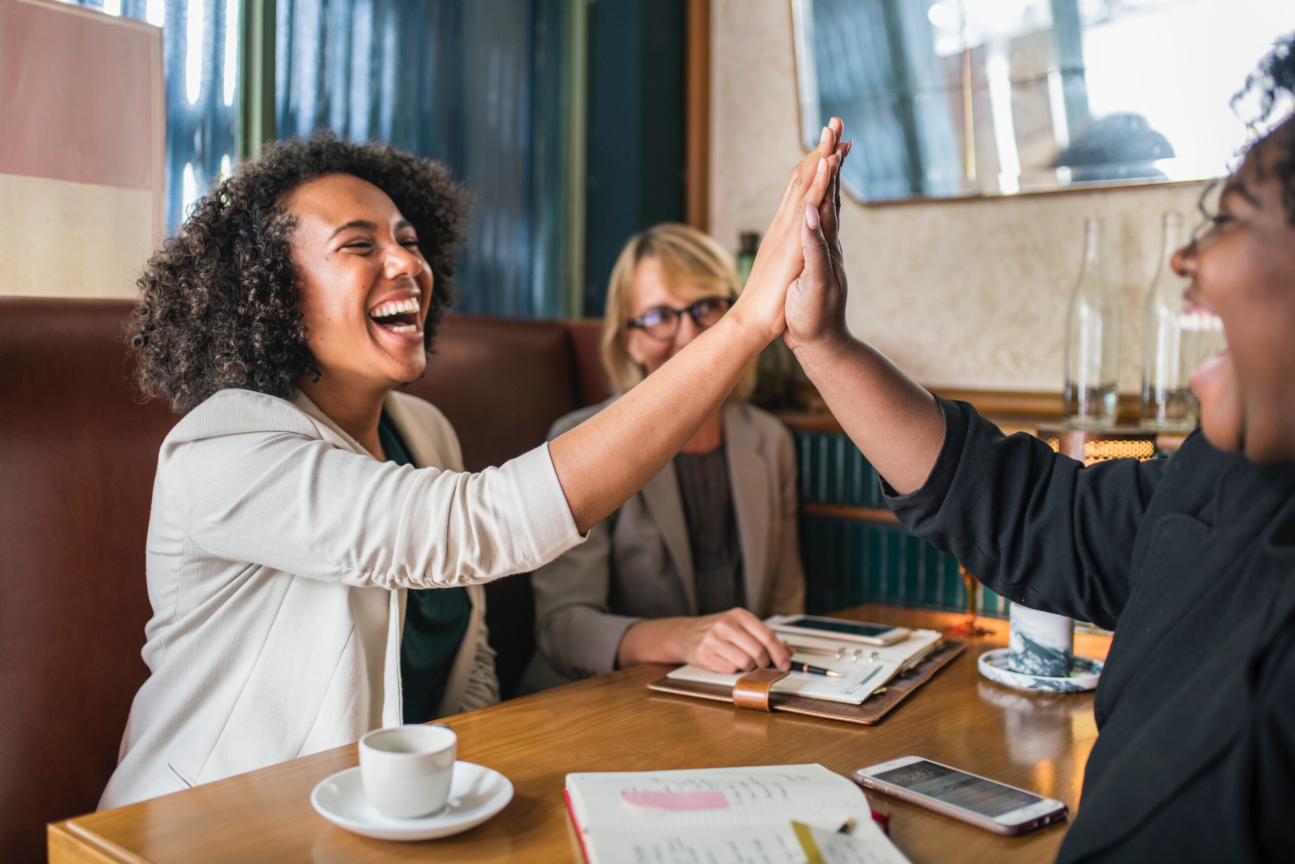 Two woman high five in a cafe