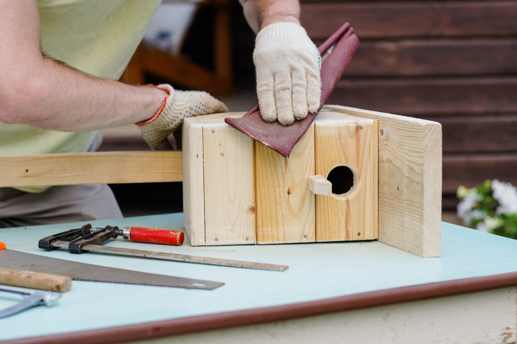 A person building a birdhouse so birds seek them out and not the other way around, which is a fitting metaphor for how employer branding helps attract new talent and retain top talent.